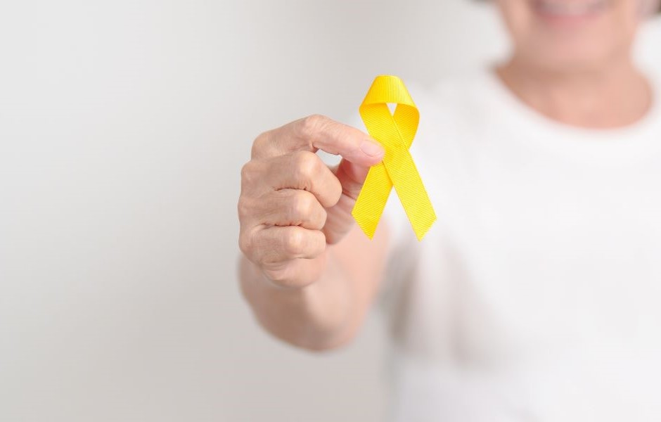 Pessoa segurando um laço amarelo, símbolo de conscientização sobre o câncer de pâncreas, com foco na campanha de conscientização e apoio à prevenção.